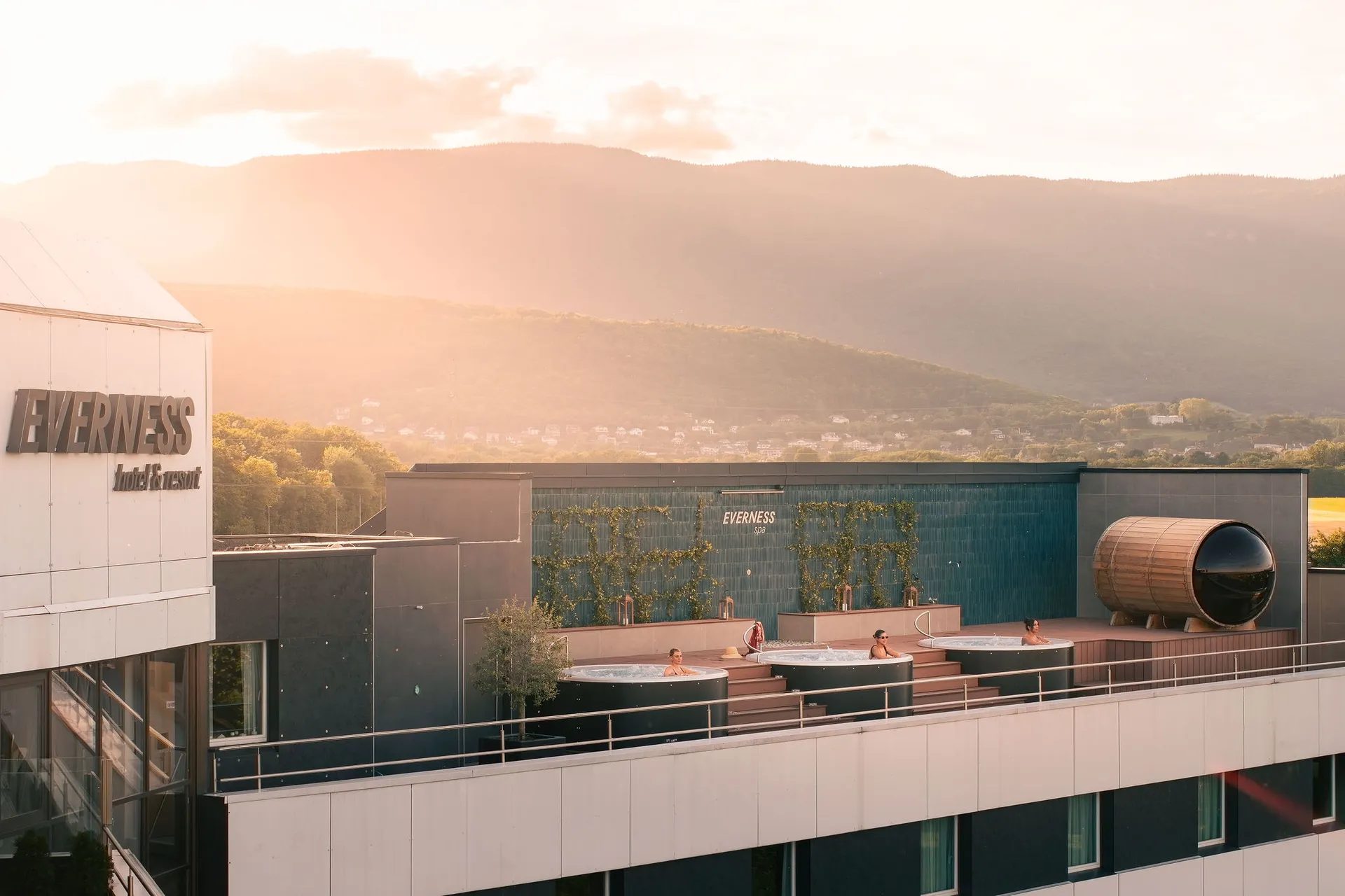 La façade d'Everness et le spa rooftop au coucher du soleil, le Jura en fond